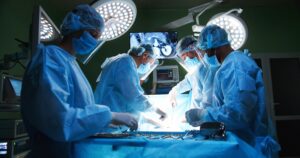 Doctors in an operating room with a screen in the background.